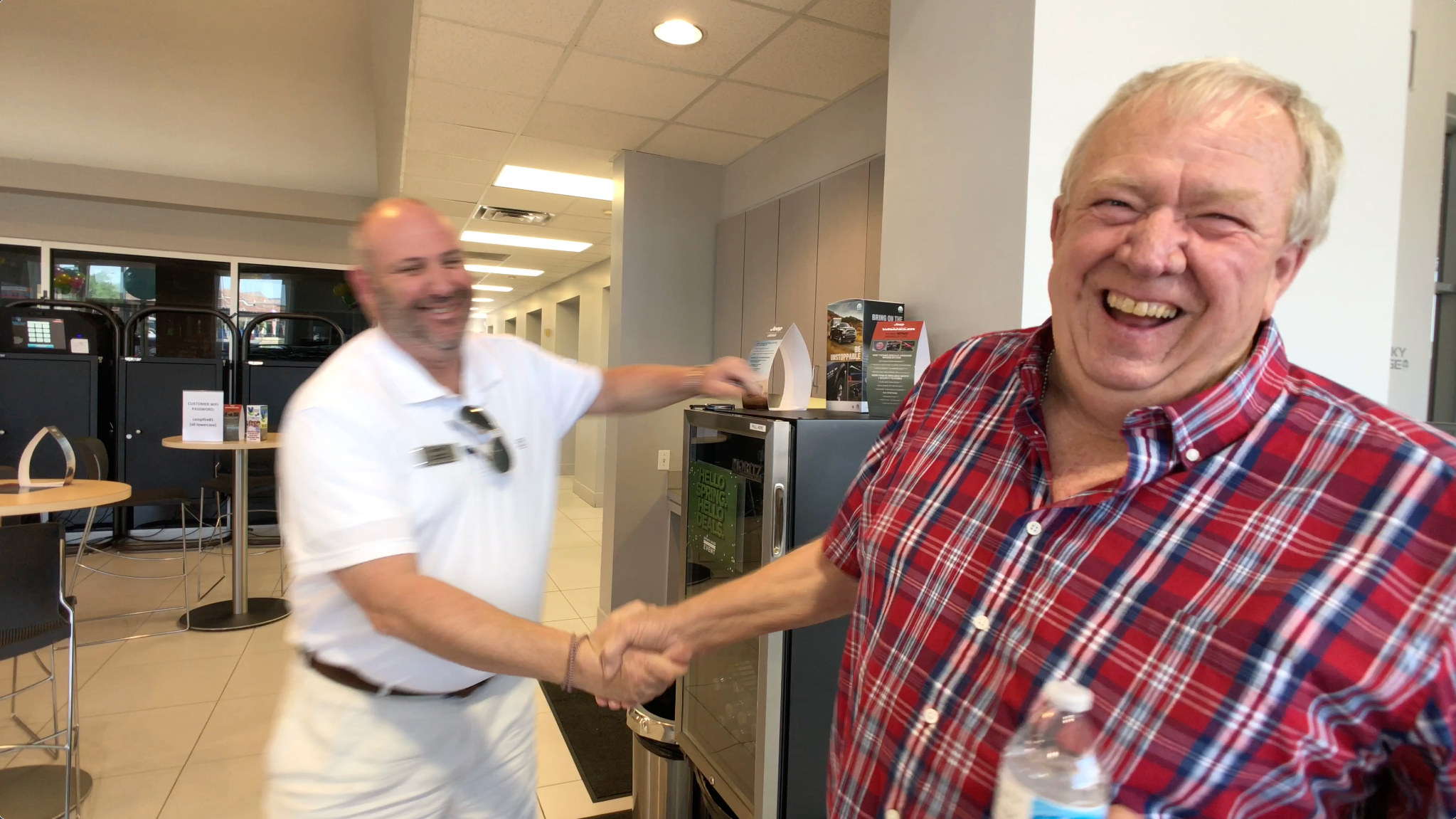 An authentic dealership moment: a customer and salesperson sharing a joyful handshake